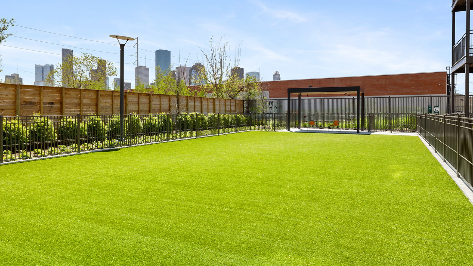 The pet park at our apartments in Houston, featuring a large astroturf area contained by a black fence.